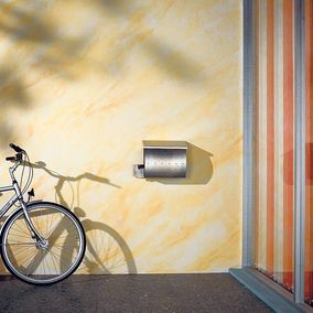 Vor einer frisch gestrichenen Wand lehnt ein Fahrrad. Die angrenzende Wand ist bunt tapeziert.