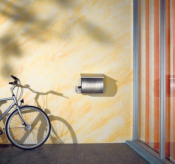 Vor einer frisch gestrichenen Wand lehnt ein Fahrrad. Die angrenzende Wand ist bunt tapeziert.