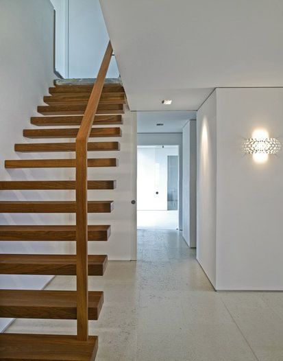 Gestaltung des Treppenhauses mit offener Holztreppe und hell gestrichenen und verputzten Wänden.